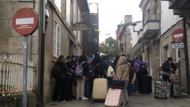 Peregrinos con maletas a la puerta de un albergue en Sarria.